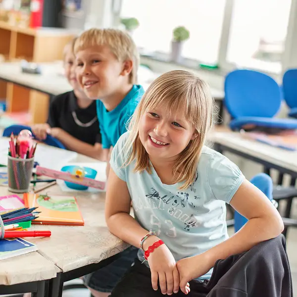 OGS-Betreuerin und Kinder malen gemeinsam an einem Tisch.