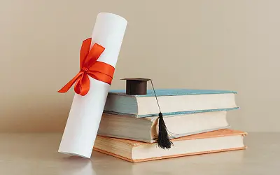 Zertifikat und Doktorhut auf Büchern.